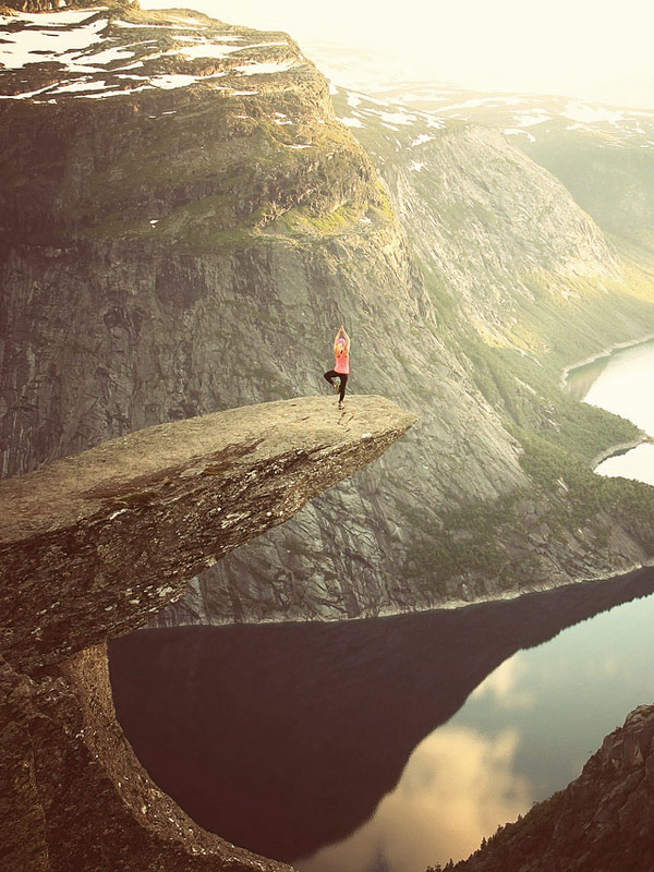 Eine Frau macht Yoga auf einem Fellsvorsprung in Norwegen